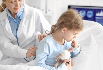 Obraz na płótnie Canvas Female doctor working with little girl in hospital room