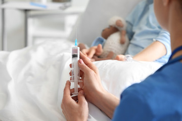 Female doctor working with little girl in hospital room