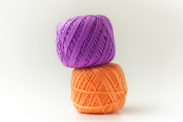 Two skeins of thread in purple and orange. Knitting threads on a white background. hobby.