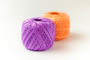 Two skeins of thread in purple and orange. Knitting threads on a white background. hobby.