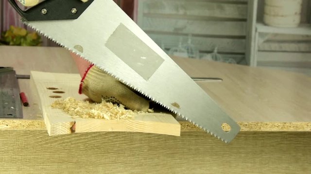 Carpenter sawing wooden plank with handsaw. Handwork, improvement