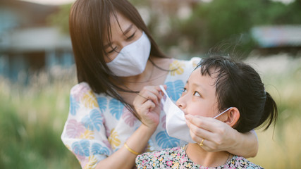 Mother help her daughter wearing face mask for protect 2019 - nCov , covid 19 or corona virus - Powered by Adobe