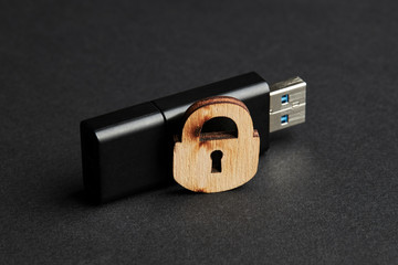 digital security for electronic privacy data concept. dark moody photo. black usb stick with wooden lock over matte background.
