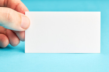 Fototapeta premium caucasian person holding business identity blank card over blue background. mockup for design.