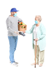 Elderly woman paying courier of food delivery company for order via terminal against white background