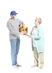 Courier of food delivery company giving products to elderly woman on white background. Concept of epidemic
