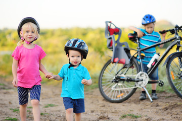 small children-boy and girl brother and sister in Bicycle helmets are holding hands on the background of a Bicycle.