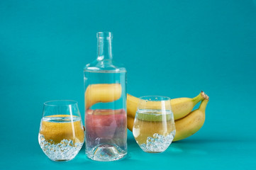 Glass water bottle and glasses. Fruit. Bananas, apples, lemon. Healthy and raw food. Taking care of your health.