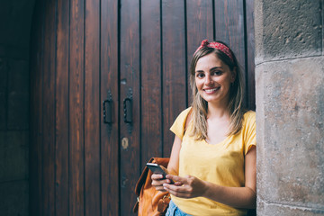 Obraz premium Smiling traveling woman using smartphone on street