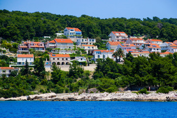 Fototapeta na wymiar Cottages near the village of Bol on the island of Brac in Croatia - Pine forest on the slopes plunging into the Adriatic Sea
