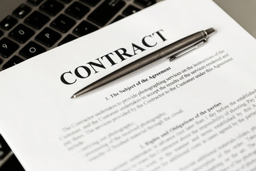 Obraz premium Pen for signing the contract. The pen and contract are on the laptop.