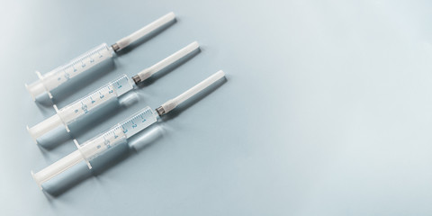 Three white syringes empty and full on a blue background. Medicine and pharmaceuticals cover copy space
