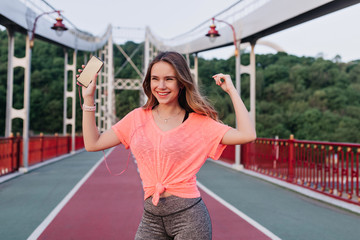 Blissful sporty girl expressing positive emotions after competition. Sensual young woman enjoying workout in spring day.