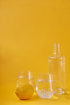 Refreshing water with lemon on a yellow background. Healthy lifestyle, thirst quenching.