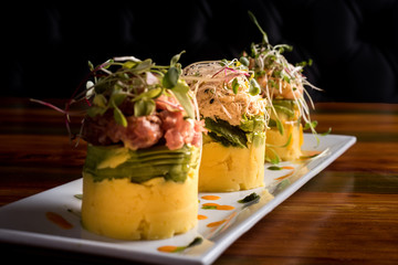 Traditional Peruvian dish called Causa made of mashed potato with aji hot pepper and lime juice and filled with vegetables corn, peas, carrots and mayonnaise Selective Focus, Focus on front