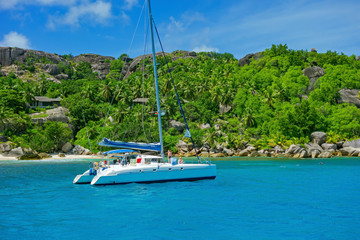 sailboat on the beach, Seychelles, little Island with palm trees with granite rocks in the ocean 