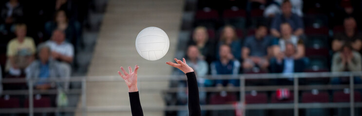 Girl Volleyball player and setter setting the ball for a spiker during a game..