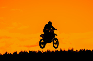 Fototapeta na wymiar Silhouette Of Motocross Rider Jump In The Sky At Sunset