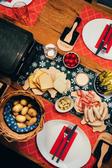 Traditional swiss food called raclette with melting cheese, cooked potatoes and grilled meat. Wooden serving boards shaped as map of Switzerland.