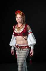 beautiful woman in traditional decorated tribal dance costume with golden necklace, circlet of flowers, red west, white sleeves and skirt looking away isolated on black