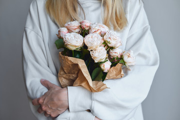 White-pink roses in the hands of a happy woman. Rose petal close-up. Beautiful holiday spring bouquet. Florist girl with blossom flower. Fresh floral bunch. Romantic surprise from a loved one