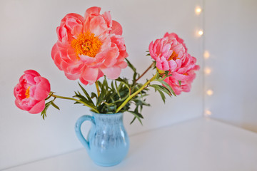 bouquet of large bright pink peonies in a blue vase on a white table, white background