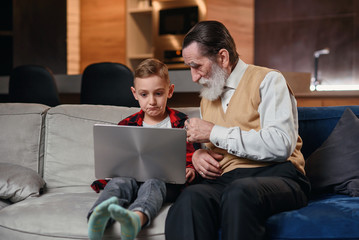 Grandson is teaching his grandfather to use laptop computer.