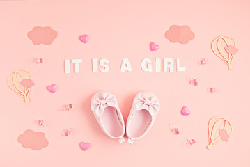 Cute newborn baby girl shoes with festive decoration over pink background. Baby shower, birthday, invitation or greeting card idea