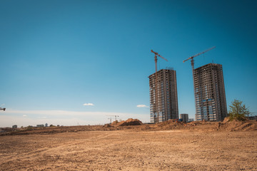 Construction of a new neighborhood. Built houses and free landscape. Tower crane and builders in action on blue sky background.