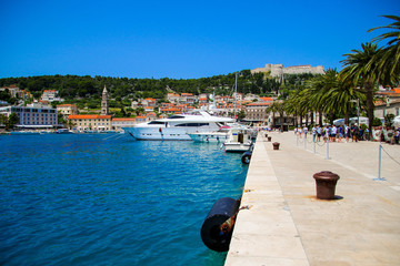 Fototapeta na wymiar Waterfront promenade on the island of Hvar in Croatia - Luxury yacht moored in an old port of the Adriatic Sea