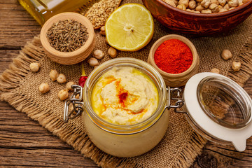 Hummus on old wooden boards background. Dry chickpea, olive oil, lemon, cumin and chili pepper