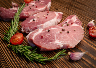 Raw meat, steak on a wooden Board. Spices, garlic, rosemary, peppers, tomato. Ready for cooking and roasting.