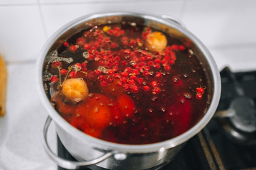 Fresh fruits are boiled in boiling water in a metal pan on the stove. Delicious stewed apricot, apples, cherries, raspberries. Photography, concept.