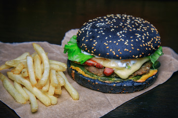 Black burger with french fries.