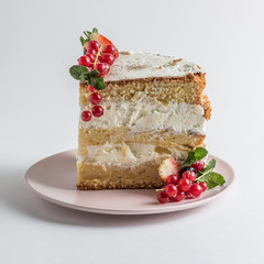 Slice of sponge cake with berries on white plate on white background. 