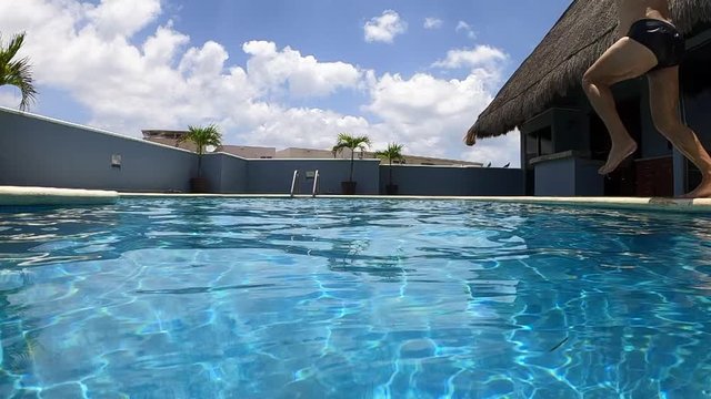Man jumps into the pool on a sunny day. Horizontal slow-motion video In Playa del Carmen, Mexico, America