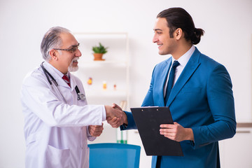 Obraz premium Young businessman meeting with old doctor