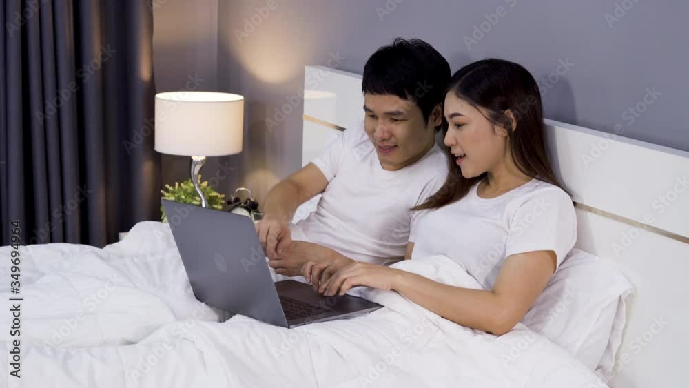 Wall mural couple using laptop together on a bed