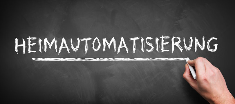 hand is writing the German word for HOME AUTOMIZATION on a blackboard