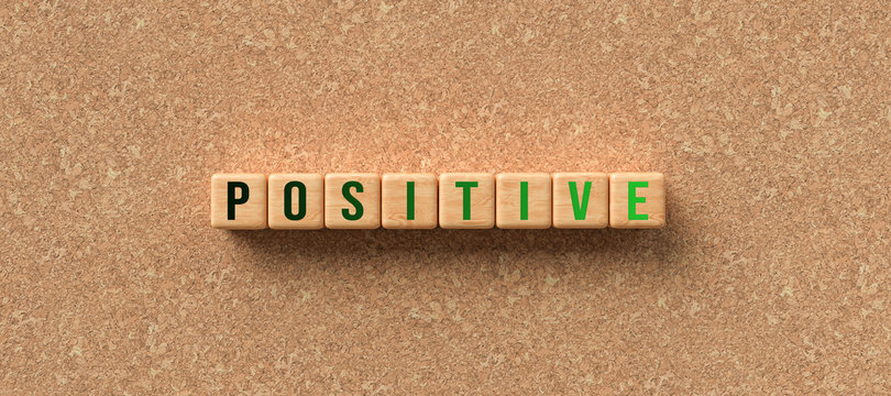 wooden cubes with the word POSITIVE on cork background