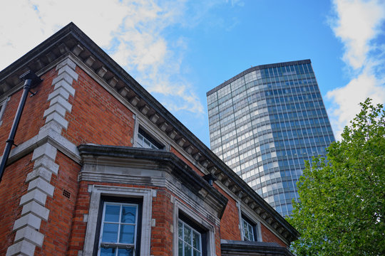 Looking up to modern Millbank Tower with older building in foreground