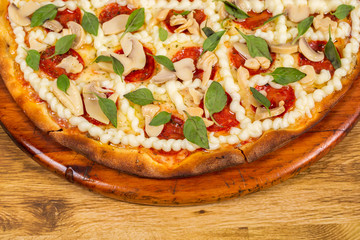 pizza with mushroom, sun-dried tomatoes, catupiry cheese and basil on wooden background