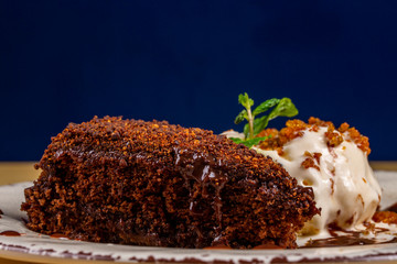 slice of chocolate cake with vanilla ice creamon blue background