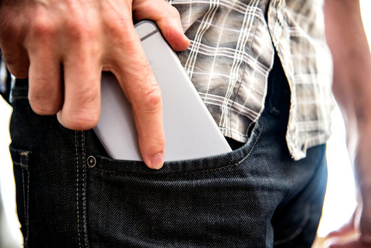 Midsection Of Man Putting Smart Phone In Pocket