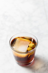 Glass of red vermouth with big ice, orange slice and olive