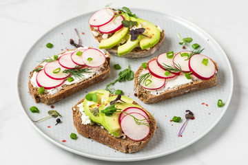 Avocado and radish toast with feta cheese, sprouts and pepper in a plate for healthy breakfast