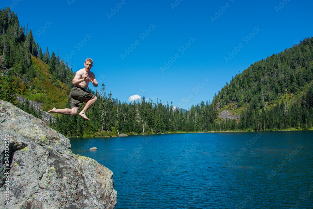 Wall mural Adventurous male hiker jumping into an alpine lake in Washington State.