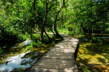 Wooden path built over the streaming waters of Krka National Park in Croatia - Hike through the forest along the flowing river among the waterfalls