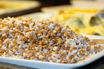 white crockery with brown rice with defocused restaurant buffet in the background
