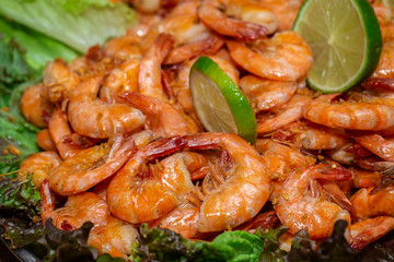 close up portion of shrimp fried in garlic and oil with lemon on wooden background